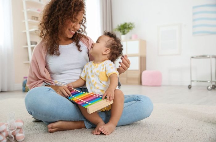 Cute baby and mother playing on floor at home