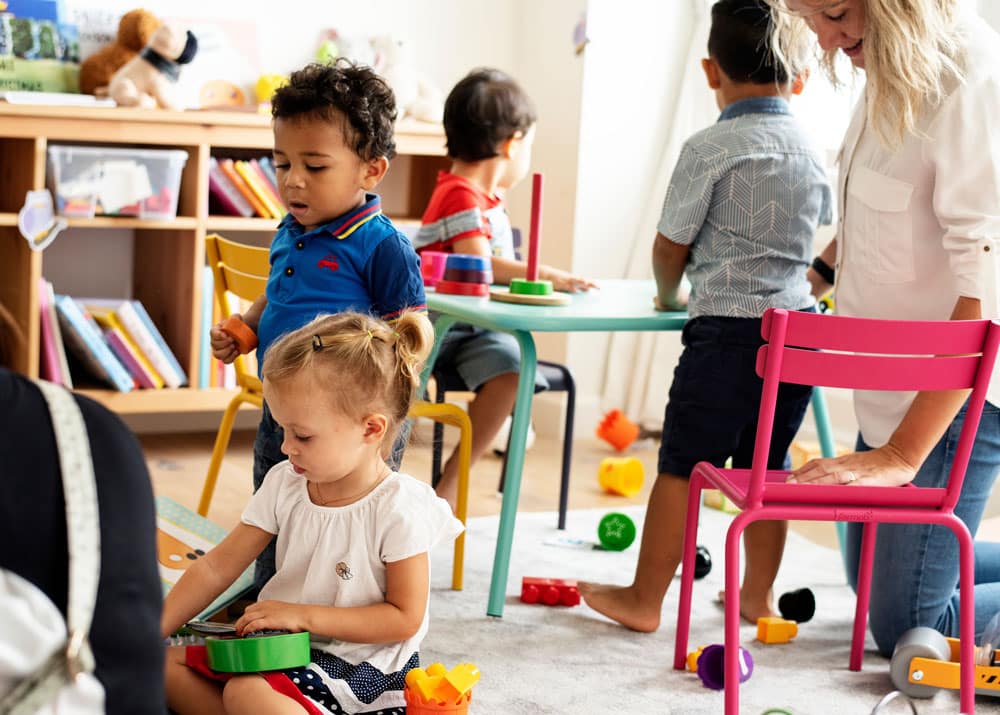 Nursery children playing with teacher in the classroom