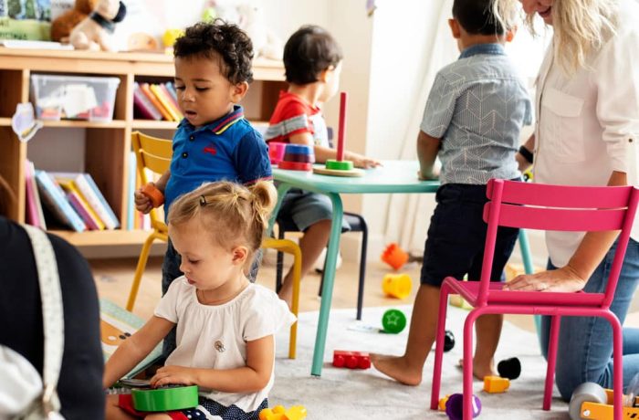 Nursery children playing with teacher in the classroom